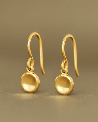 Pair of gold earrings on a beige background