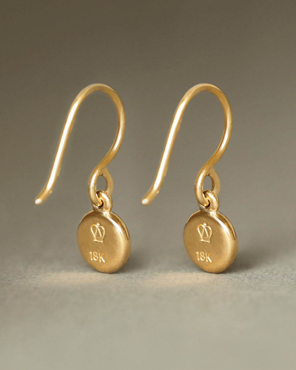 Solid 18k gold dangle earrings with a soft concave button hanging from 18k gold french wires