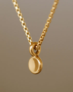 solid 18k gold circle button pendant hanging from 14k gold box chain