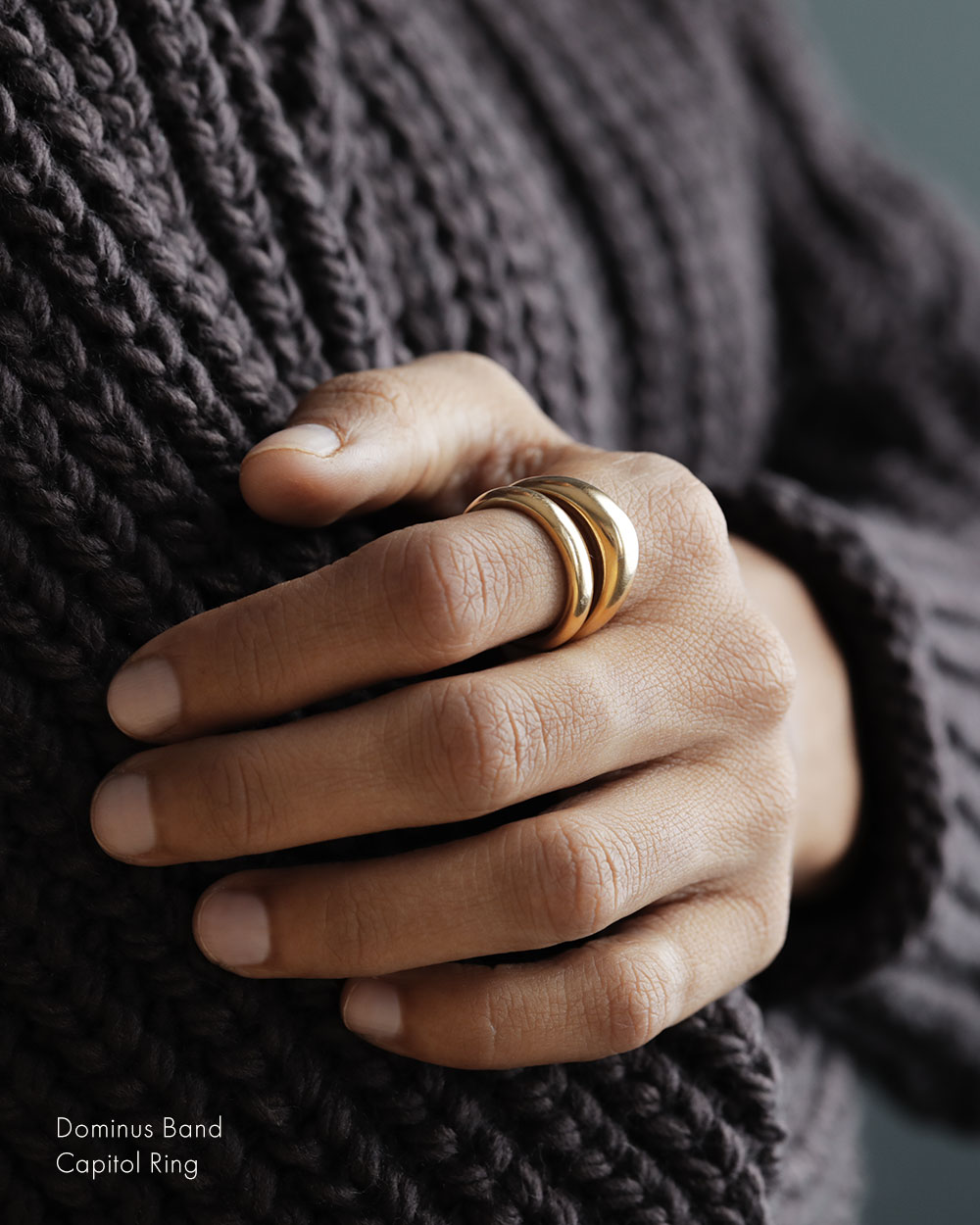 Woman in hand knit sweater, wearing solid 18k yellow gold dome-shaped ring for weddings and milestones. Soft curves. Heavy.