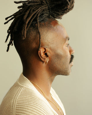 Man wearing pair of solid 18k yellow gold hoop earrings with a soft dome shape. Part of the George Rings Capitol Collection.