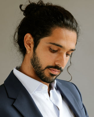 Man in suit showing ear wearing Pair of solid 18k yellow gold hoop earrings with a soft dome shape. Part of the George Rings Capitol Collection.