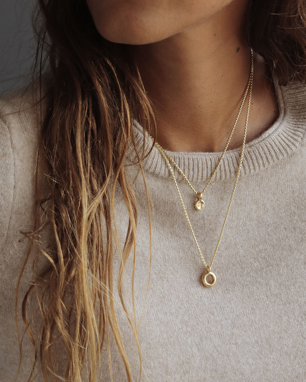 Solid 18k yellow gold donut pendant hanging on a 14k gold box chain layered with the Button pendant. Soft and heavy.