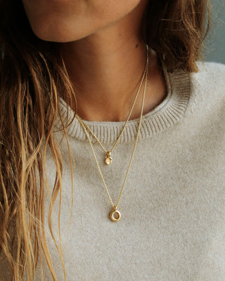 Solid 18k yellow gold donut pendant hanging on a round box chain layered with the Button pendant. Soft and heavy.