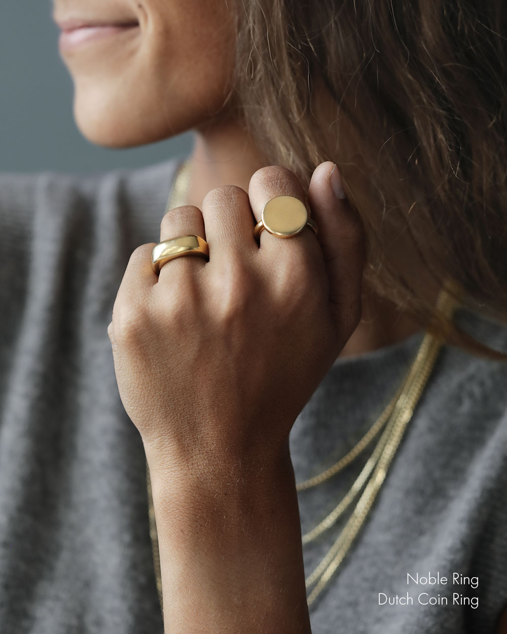 White woman with her hand on her chin, wearing a solid 18k yellow gold heavy ring. Noble Ring by George Rings for men, women, and all genders.