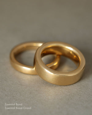 Heavy mens wedding band in solid 18k yellow gold, laying on gray paper. Essential Grand Band by George Rings.