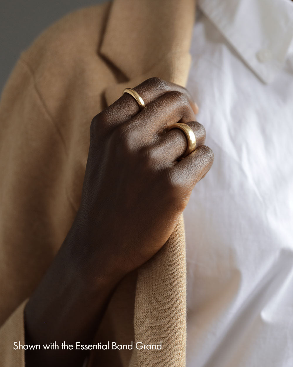 Woman wearing solid 18k yellow gold slim donut-shaped band on her index finger and large heavy rounded square 18k yellow gold band on ring finger.