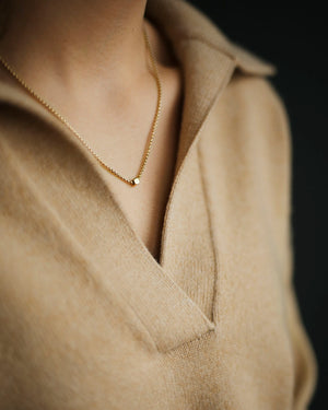 Woman in cashmere sweater wearing Gold Cube Necklace by Carol Leskanic George Rings small cube on 14k round box chain