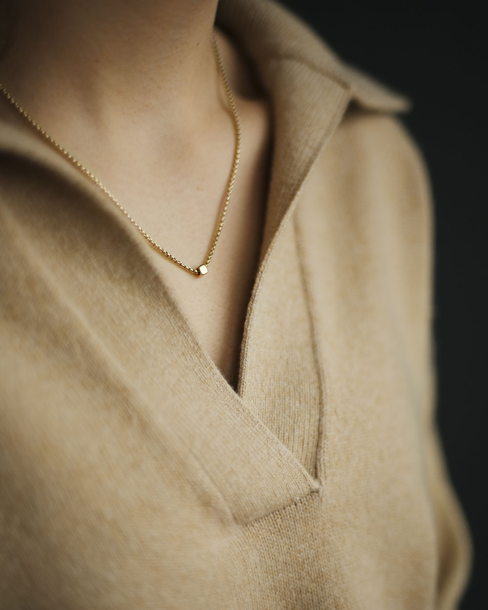 Woman in cashmere sweater wearing Gold Cube Necklace by Carol Leskanic George Rings small cube on 14k round box chain