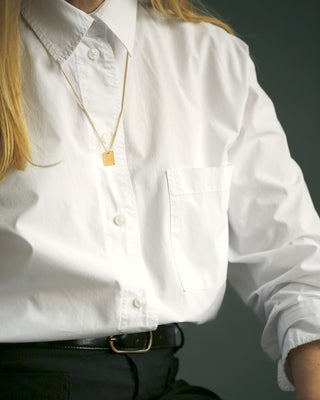Woman in white shirt wearing a Gold Luggage Tag necklace by Carol Leskanic and George Rings 14k round box chain