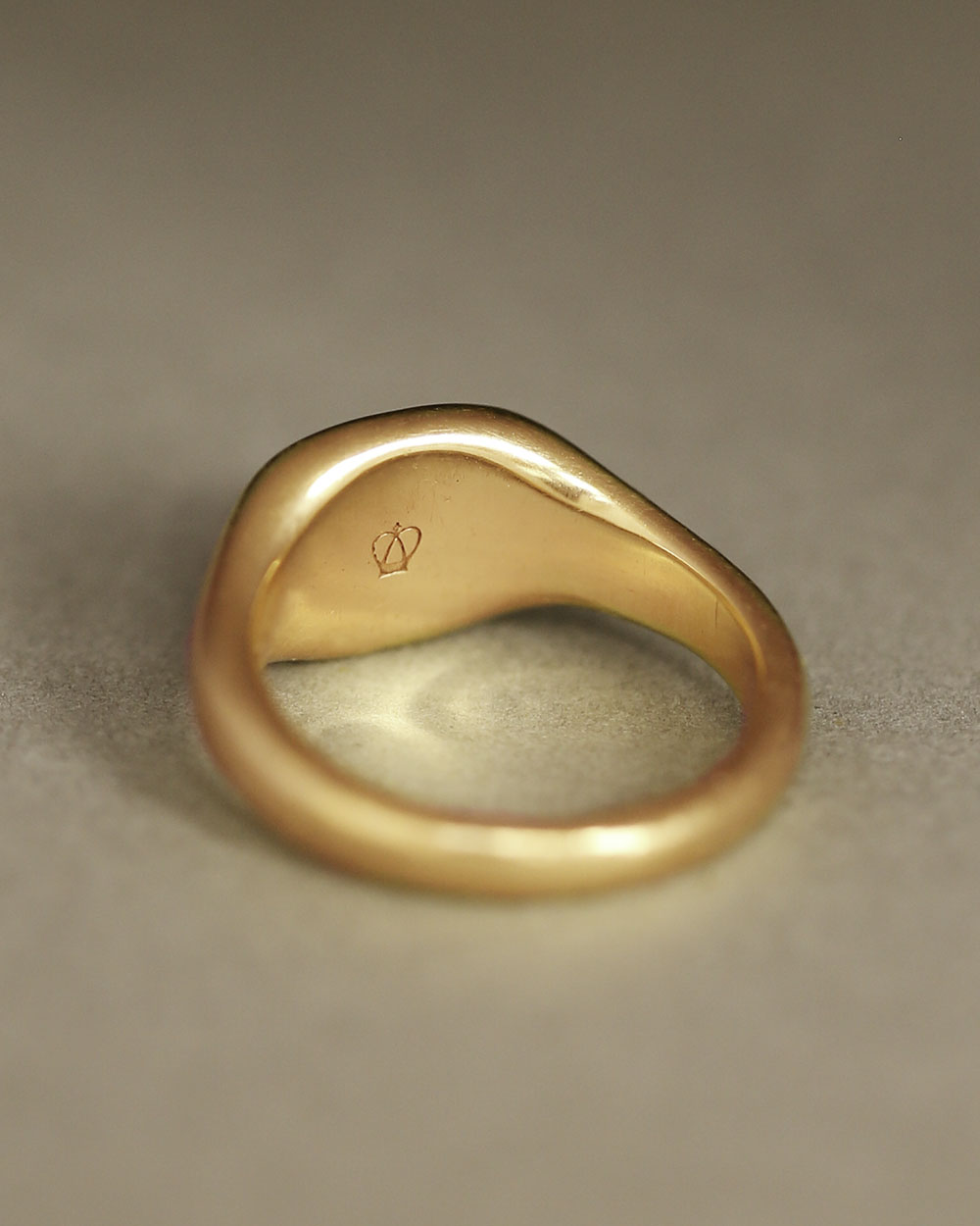 Solid 18k yellow gold heavy signet ring on gray paper. Hugo Signet Ring by George Rings.