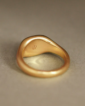 Solid 18k yellow gold heavy signet ring on gray paper. Hugo Signet Ring by George Rings.