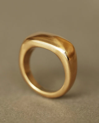 Solid 18k yellow gold heavy ring upright on gray paper. Noble Ring by George Rings for men, women, and all genders.