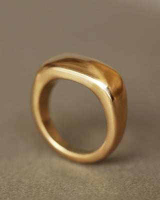 Solid 18k yellow gold heavy ring upright on gray paper. Noble Ring by George Rings for men, women, and all genders.