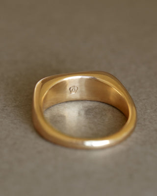 Solid 18k yellow gold heavy ring upright on gray paper. Noble Ring by George Rings for men, women, and all genders.