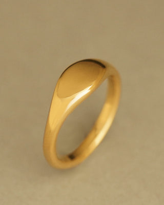 A polished gold signet ring with a smooth, rounded, oval profile. Oval Pinky Ring by George Rings. Cast in solid 18K yellow gold.