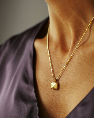 Solid 18k yellow gold pillow puff pendant hanging from a solid 14k yellow gold box chain. Pillow Pendant by George Rings.