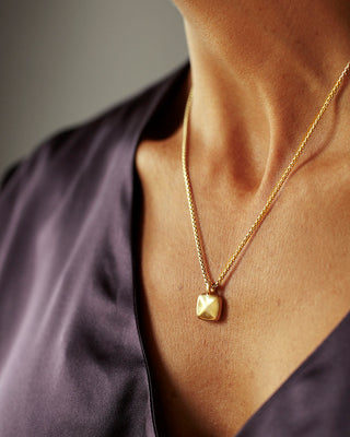 Solid 18k yellow gold pillow puff pendant hanging from a solid 14k yellow gold box chain. Pillow Pendant by George Rings.