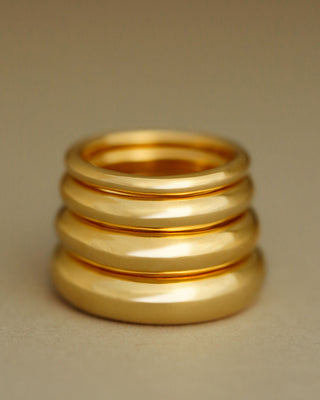 A tall stack of gold rings. Stack of bands by George Rings, cast in solid 18K yellow gold.