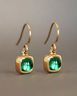 A pair of green emerald rounded square gems inside solid 18k yellow gold bezels hanging from gold french wires.