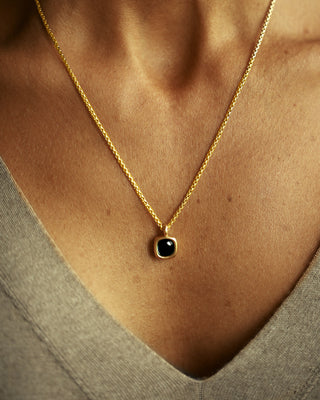 A moody black green tourmaline rounded square gem inside a solid 18k yellow gold bezel. Sovereign Pendant by George Rings.