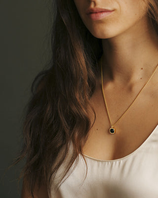 A moody black green tourmaline rounded square gem inside a solid 18k yellow gold bezel. Sovereign Pendant by George Rings.