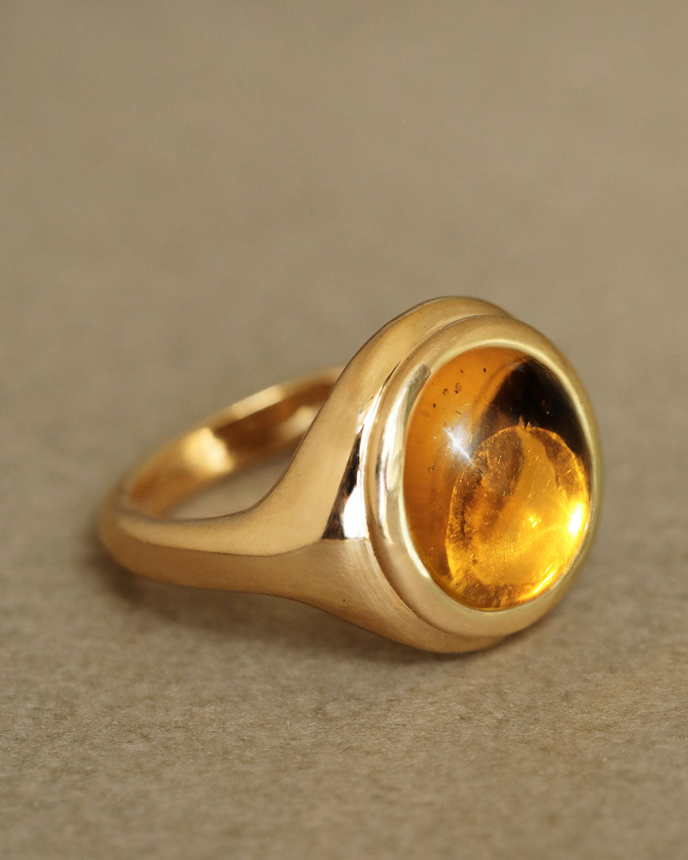 Golden large round cabochon citrine gem sits inside large round 18k solid yellow gold signet ring. The Monarch by George Rings.