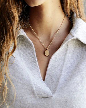 Woman wears a soft v-neck sweater and Golden 8 sided pendant with large bail and chain. Solid 18k gold, thick and substantial. Round box cut 14k gold chain.